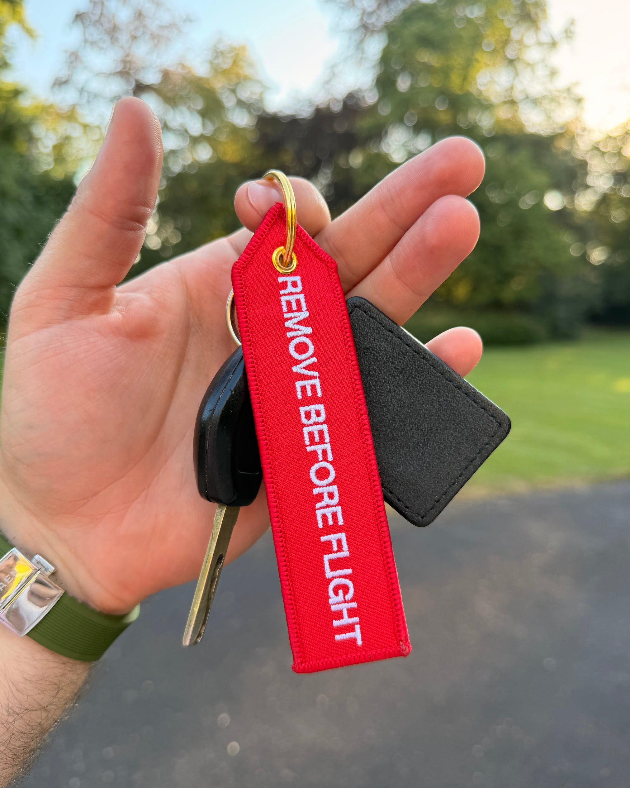 Roter "Remove before Flight" Schlüsselanhänger mit goldenem Ring am Autoschlüssel