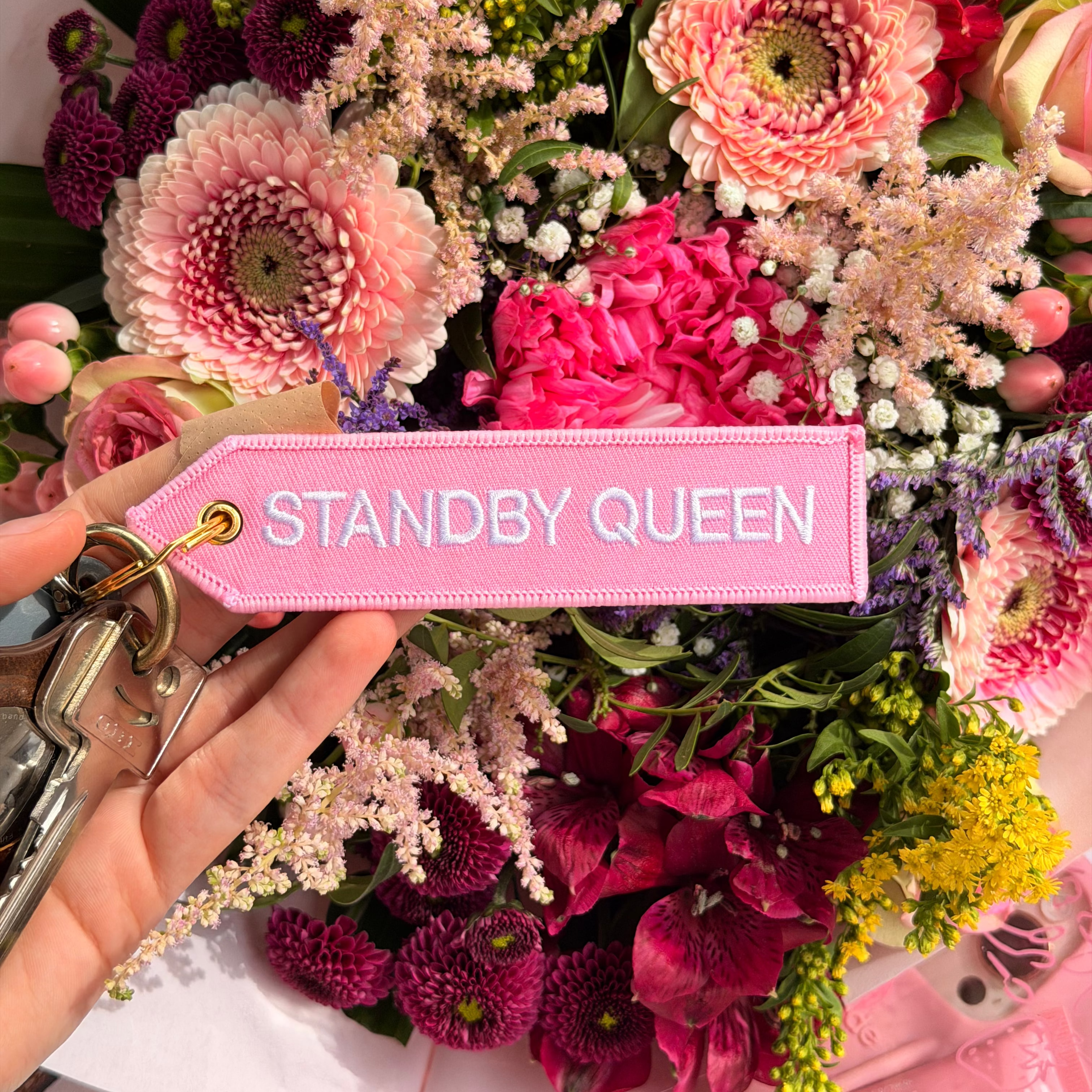 Rosa Schlüsselanhänger Standby Queen vor buntem Blumenstrauss