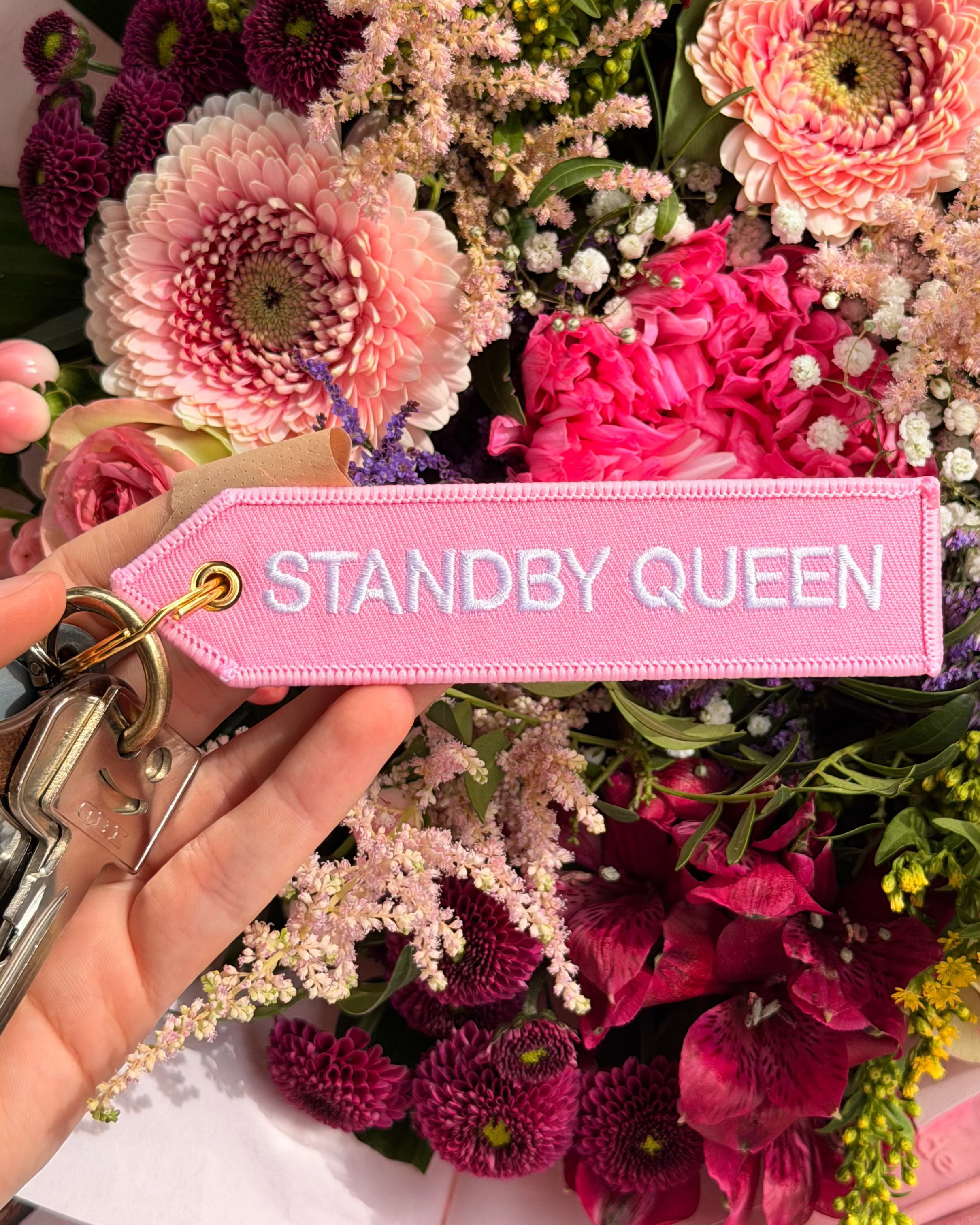 Rosa Schlüsselanhänger Standby Queen vor buntem Blumenstrauss