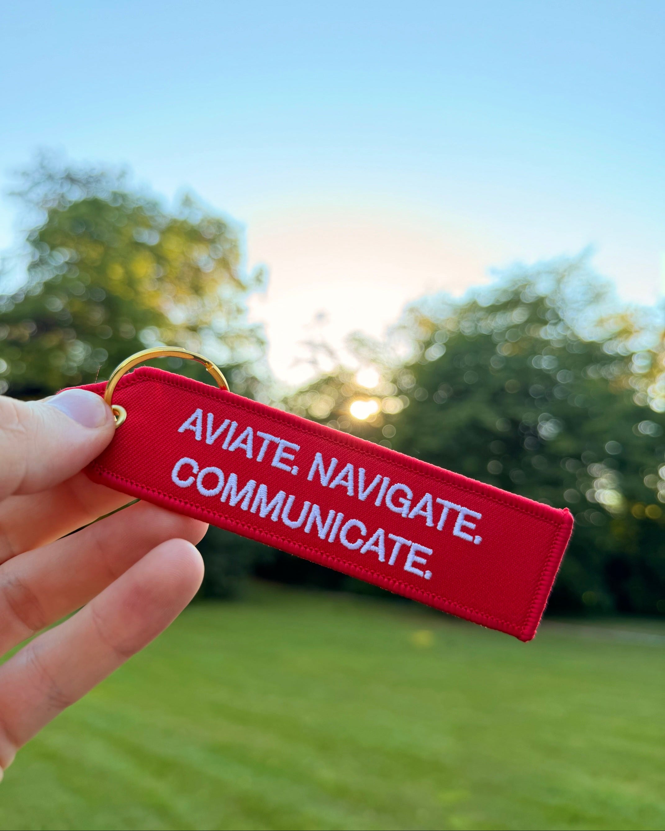 Roter "aviate. navigate. communicate." Luftfahrt Schlüsselanhänger mit goldenem Ring im Luftfahrt Style
